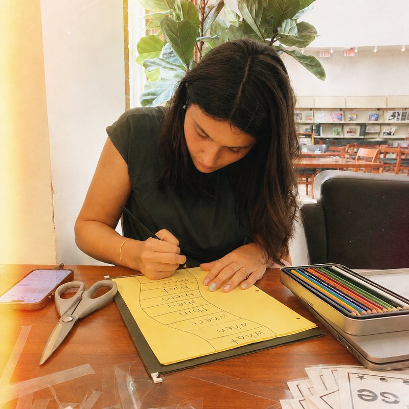 Danika laying out lesson materials &mdash; word cards and a hand-drawn phonics sheet.